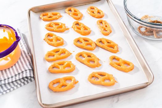 Dipping pretzels twists into melted chocolate to make chocolate-covered pretzel twists.