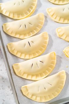 Brushing uncooked empanadas with blueberries with egg wash.