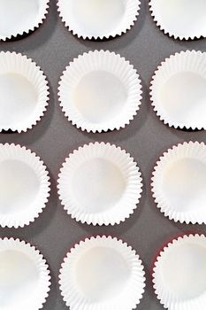 Lining cupcake pan with foil cupcake liners to bake red velvet cupcakes with white chocolate ganache frosting.