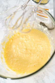 Mixing ingredients with a hand mixer in a large mixing bowl to bake mini vanilla cupcakes with ombre pink buttercream frosting.