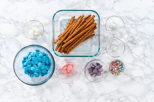 Ingredients in glass mixing bowls to prepare mermaid chocolate pretzel rods.