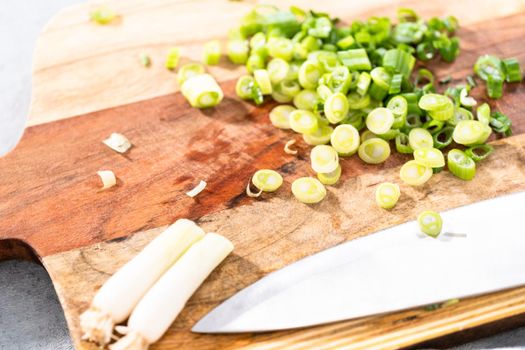 Cutting organic green onions on a wood cutting board.