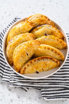 Freshly baked sweet empanadas with blueberries on the kitchen counter.