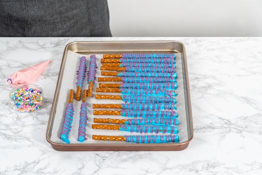 Drizzled with chocolate pretzel rods drying on a baking sheet lined with parchment paper.