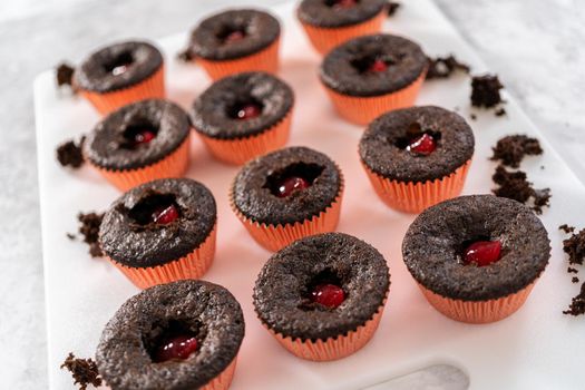 Filling freshly baked chocolate cupcakes with strawberry filling.