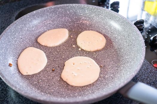 Frying small pancakes on a kefir base in a frying pan.