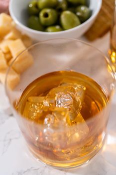 Scotch on the rocks in whiskey glass on a white marble surface.