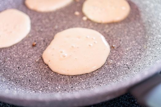 Frying small pancakes on a kefir base in a frying pan.