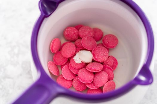 Melting chocolate melts in a candy melting pot to prepare gourmet mini chocolates with sprinkles.