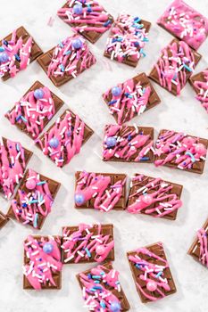 Gourmet dark mini chocolates with drizzled pink chocolate and fancy sprinkles on top.