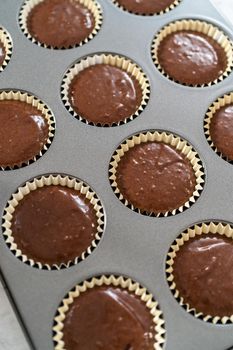 Filling up foil cupcake liners with a chocolate cupcake batter to bake s'mores cupcakes.