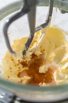 Mixing ingredients in kitchen electric mixer to make ombre pink buttercream frosting.