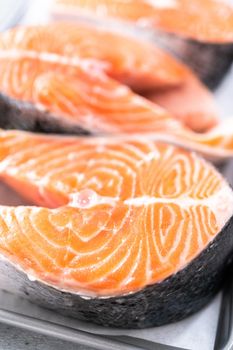 Farm-raised salmon steaks on a cooking tray with a parchment paper.