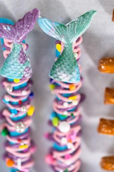 Mermaid chocolate pretzel rods drizzled with pink and purple chocolate and covered with sprinkles.