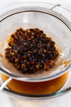 Draining freshly cooked boba pearls through a mesh strainer.