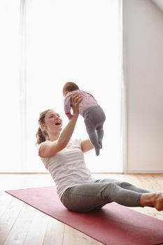 Yoga and baby-lifting the perfect workout. an attractive young woman bonding with her baby girl while doing yoga
