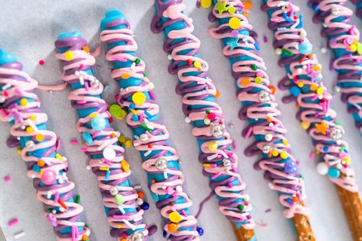 Mermaid chocolate pretzel rods drizzled with pink and purple chocolate and covered with sprinkles.