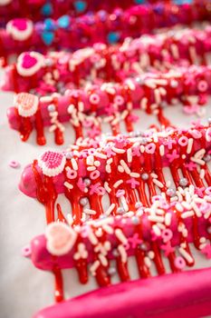 Drizzling melted chocolate over chocolate-dipped pretzels rods and decorating with sprinkles to make chocolate-covered pretzel rods for Valentine's Day.