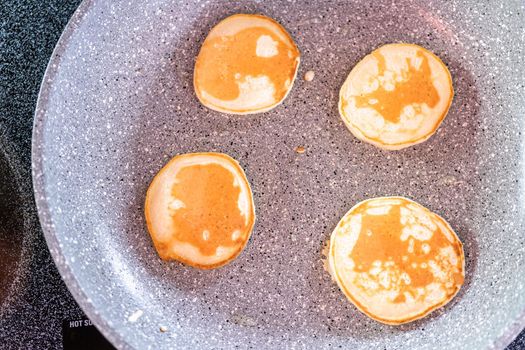 Frying small pancakes on a kefir base in a frying pan.