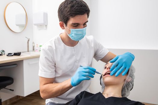 Dentist examining patient teeth with mirror in dentist clinic. Having dental checkup