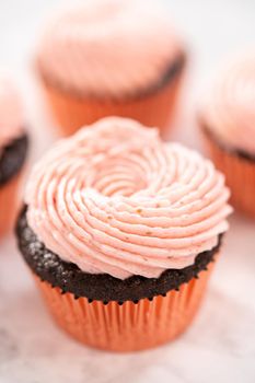 Chocolate cupcakes frosted with strawberry buttercream frosting.