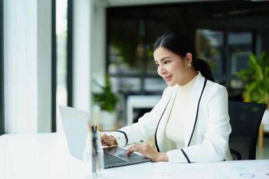 Portrait of a woman using a computer with budget documents to work on analyzing marketing plans and making plans to increase company profits.