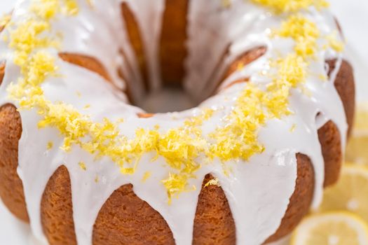 Lemon bundt cake decorated with lemon zest on a cake stand.