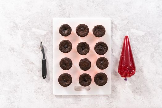 Flat lay. Filling freshly baked chocolate cupcakes with strawberry filling.