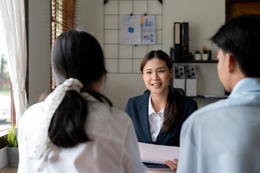 Asian female Real Estate agent offer home ownership and life insurance to young couple