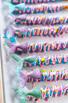 Mermaid chocolate pretzel rods drizzled with pink and purple chocolate and covered with sprinkles.