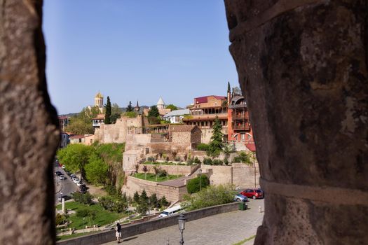 City landscape, an unusual view of the old city of Tbilisi through thick stone walls. Sunny, summer day, city center, famous view