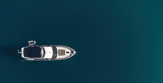 Aerial boat race. Luxury cruise trip. View from above of white boat on deep blue water. Aerial view of rich yacht sailing sea. Motor boat racing wave. Summer journey on luxury ship