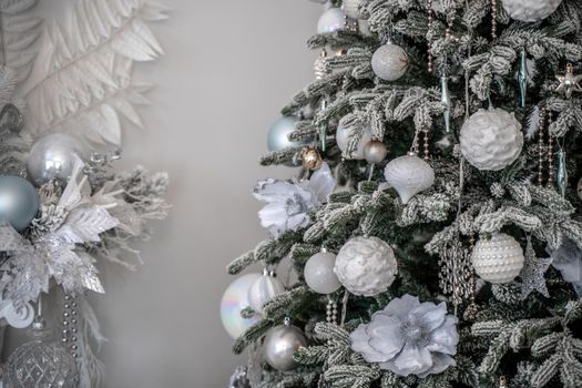 Close-up of a festively decorated outdoor Christmas tree with balls on a blurred sparkling fairy background. Defocused garland lights, bokeh effect