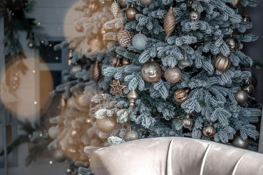 Close-up of a festively decorated outdoor Christmas tree with balls on a blurred sparkling fairy background. Defocused garland lights, bokeh effect