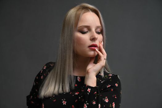 Pretty smiling joyfully female with blondy hair. Studio shot of good-looking beautiful woman isolated against gray studio wall.