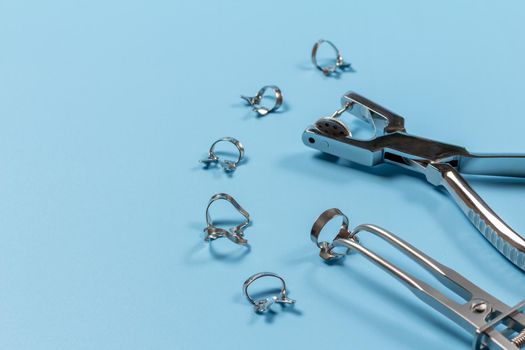 Dental hole punch, the rubber dam forceps and the clamps on the blue background. Medical tools concept.