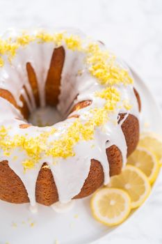 Lemon bundt cake decorated with lemon zest on a cake stand.