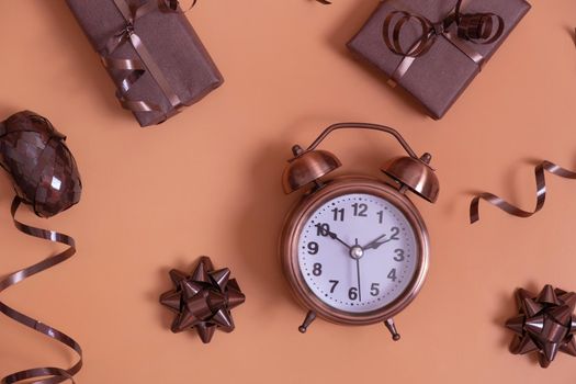 Flat lay alarm clock and gift boxes on color background. Christmas composition top view.