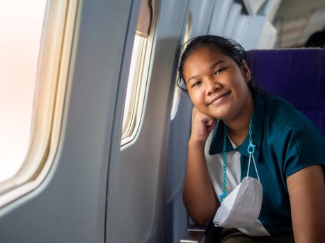 Asian woman smiling at the window of an airplane