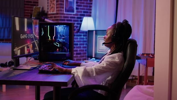 African american gamer girl streaming first person shooter tournament angry after losing online competition on gaming pc at home. Woman playing online action game unhappy after failing level.
