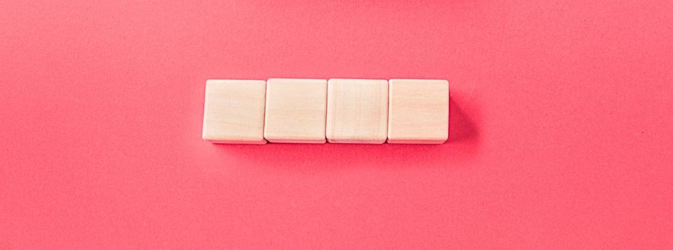 Wooden cubes isolated on pastel pink background with a place to insert text