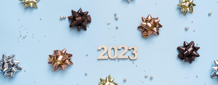 Banner with numbers 2023 on bright festive background with bows and beads top view. Christmas background flat lay.