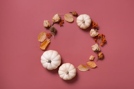 Autumn flat lay wreath of pumpkin, leaves and flowers with berries top view with copy space.