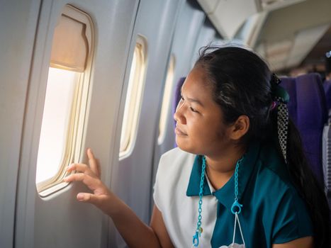 Asian woman sitting looking out of plane window