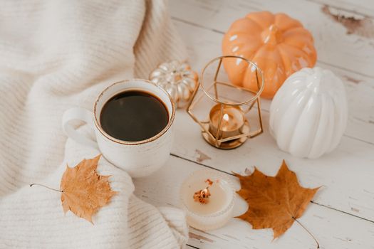 Details of Still life, cup of tea or coffee, pumpkins, candle, brunch with leaves on white table background, home decor in a cozy house. Autumn weekend concept. Fallen leaves and home decoration