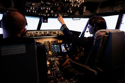 Captain and copilot switching power engine buttons on dashboard and control panel navigation to fly plane from cockpit. Pushing lever and switch with radar compass on windscreen, flying jet.