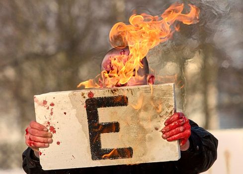 A special forces soldier covered in blood holds a burning sign with the letter e. During military exercises in the Republic of Belarus.