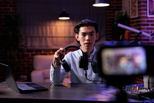 Content creator recommending headphones product on camera, recording video for internet channel on social media. Broadcasting online review vlog with audio headset, livestreaming equipment.