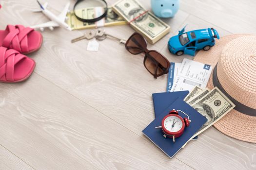 A piggy bank with dollar bills in a travel setting. In the composition of the image: Sun Hat, Alarm Clock. Concept of saving money for traveling on vacation