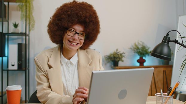 Businesswoman freelancer enters office start working on laptop computer at desk and drinking morning coffee. Woman works on notebook, sends messages makes online purchases watching social media movies
